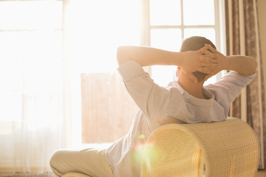 Rear,View,Of,Man,Relaxing,On,Chair,At,Home